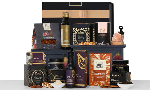 A gourmet food gift basket containing various items including bottles of wine, chocolate boxes, and other food products arranged in a decorative display.