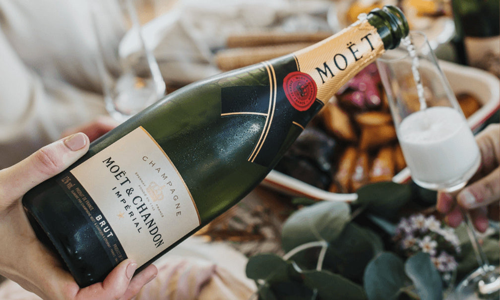 Photo of a person pouring a bottle of Moet Wine into a Glass Wine cup